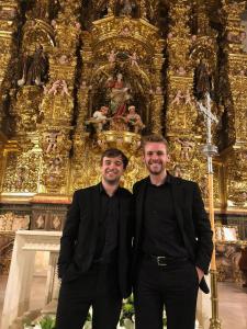 Schola singers Joseph Kemper and Charlie Littlewood pause in front of the Baroque altarpiece in Burgos Cathedral