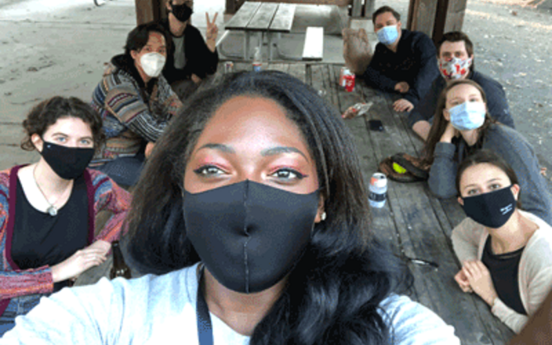 Students sitting at a picnic table with masks