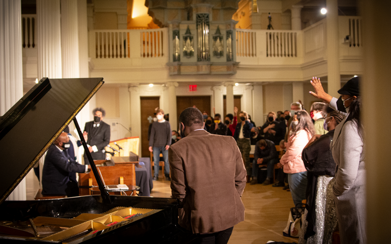 Derrick Jackson plays organ before Cornel West, Nathaniel Gumbs, lively crowd