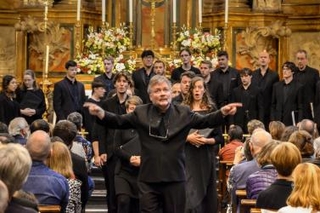 Schola conductor David Hill conducts the final notes of Path of Miracles while leading the choir out in procession 