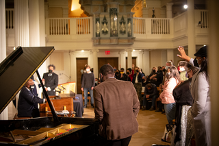 Derrick Jackson plays organ before Cornel West, Nathaniel Gumbs, lively crowd