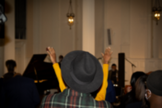 person with hands raised in gospel performance